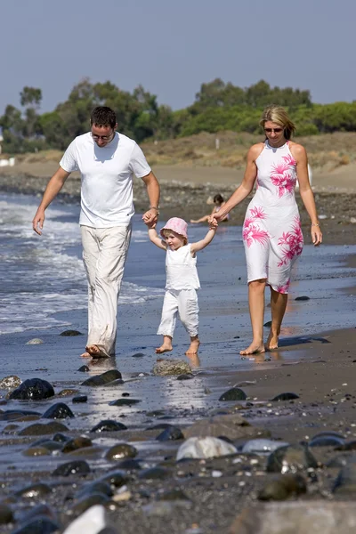 日当たりの良い海岸に沿って歩く若い、健康な家族 — ストック写真