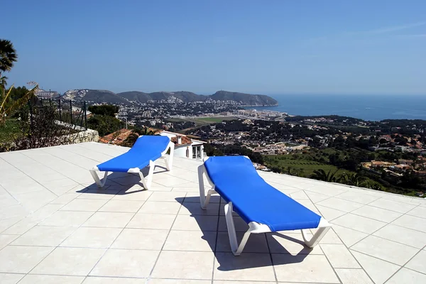 Duas espreguiçadeiras azuis no terraço ao sol com vistas incríveis sobre o — Fotografia de Stock