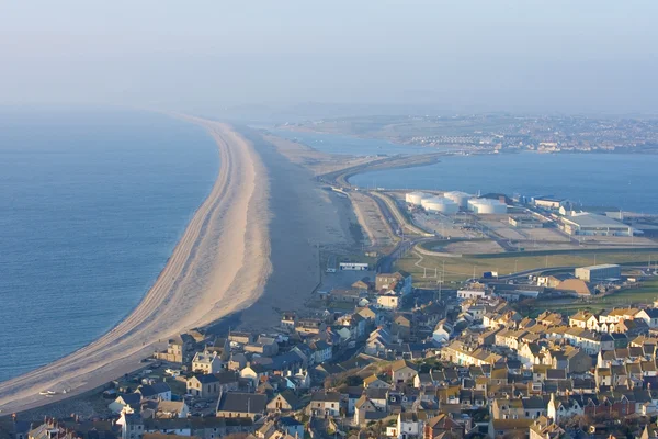 Looking west along Chesil beach from the Isle of Portland on a sunny day  with an onshore wind that has created some surf. Some anglers can be seen  fis Stock Photo 