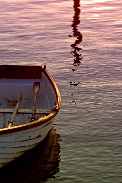 Barco de remos viejo con remos en el mar durante la puesta del sol — Foto de Stock