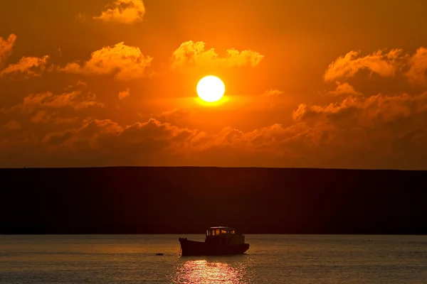 夕焼けの海にアウトの途中で小型漁船 — ストック写真
