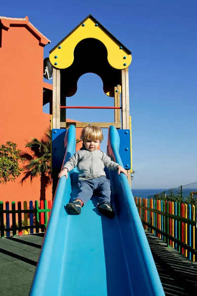 Giovane ragazzo o bambino che scende uno scivolo al sole — Foto Stock