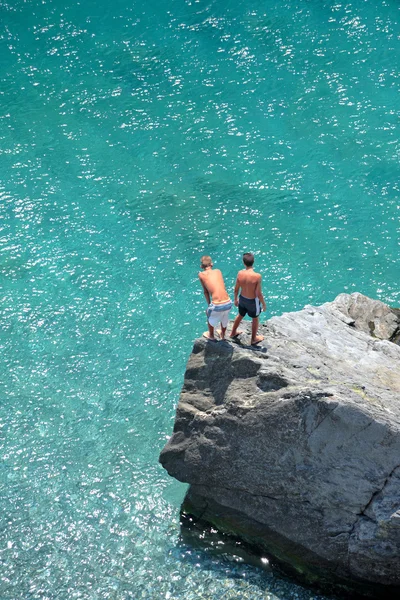 Foto aerea di due giovani ragazzi sulla roccia che guardano in mare Immagini Stock Royalty Free