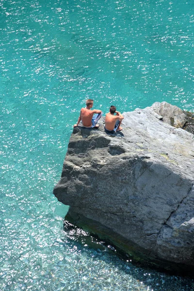 Foto aérea de dois meninos na rocha olhando para o mar Fotografia De Stock