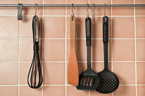 Кухонные принадлежности, висящие на крюках на стене — стоковое фото