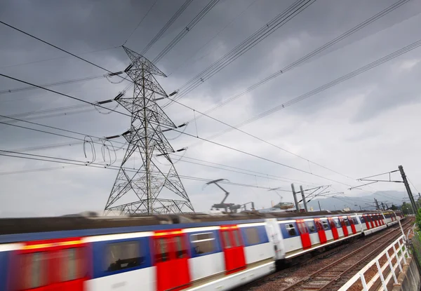 Пассажирские поезда в движении и энергетическая башня на заднем плане — стоковое фото