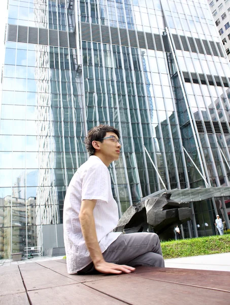 Empresário sentado em um banco em frente a um prédio de escritórios — Fotografia de Stock