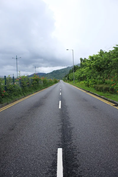 Longa estrada que se estende para fora na distância sob um azul dramático — Fotografia de Stock
