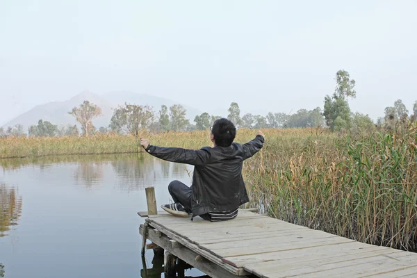 Man resting on a pontoon by a lake — Stock Photo, Image