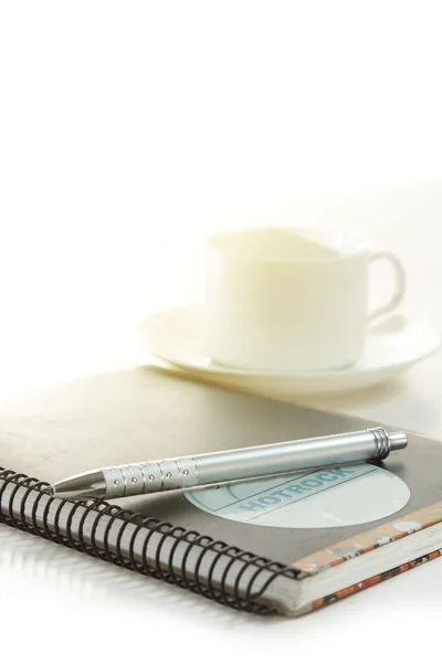 Caneta sobre um livro branco com xícara de café — Fotografia de Stock