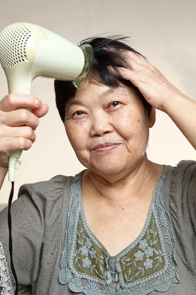 Vrouwelijke drogen haar haren met droger — Stockfoto