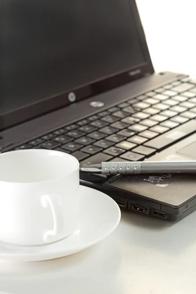 En kopp kaffe och en penna på en bärbar dator — Stockfoto
