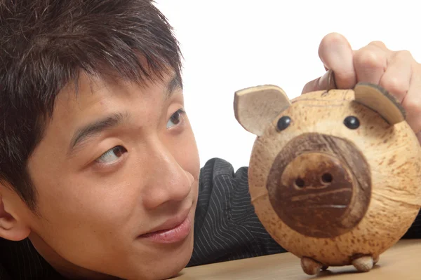 Ásia homem com porquinho banco — Fotografia de Stock