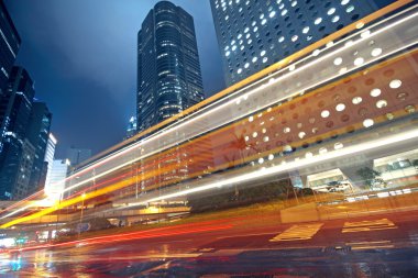 Traffic light trails in the street by modern building clipart