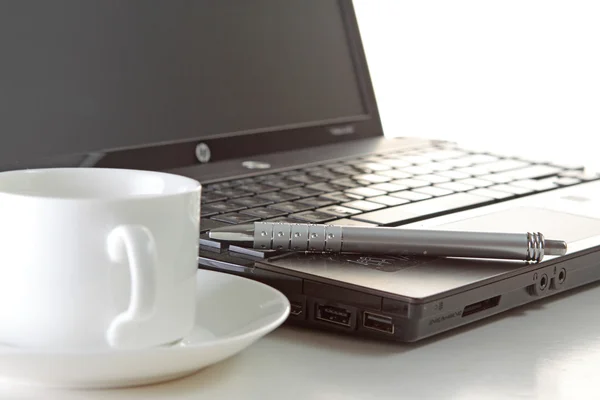 Чашка кофе и ручка на ноутбуке — стоковое фото