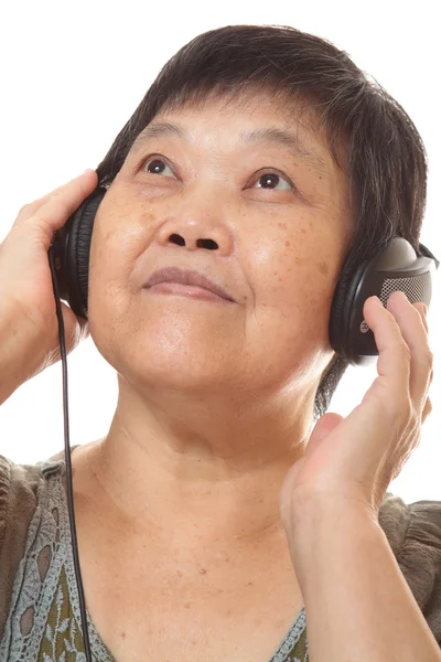Äldre kvinna lyssna på musik med hörlurar — Stockfoto