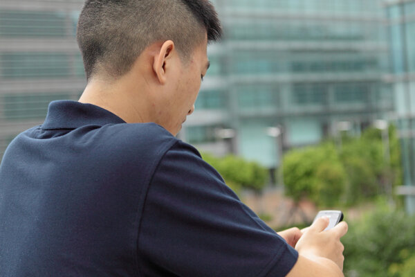 Asian man typing a message on mobile phone.