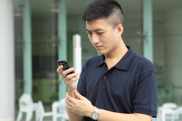 Asiático homem digitando uma mensagem no telefone móvel . — Fotografia de Stock