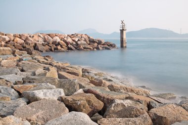 Lighthouse on a Rocky Breakwall: A small lighthouse warns of a r clipart