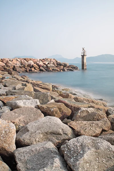 Lighthouse on a Rocky Breakwall: A small lighthouse warns of a r — Stock Photo, Image