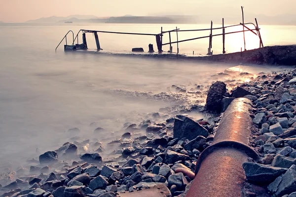 Old metal pipe and road to sea — Stock Photo, Image