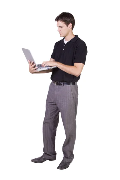Genç adam dizüstü bilgisayarda ayakta ve çalışıyor. — Stok fotoğraf