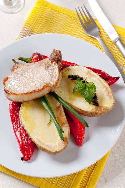 Pečené vepřové kotlety s brambory a červené papriky — Stock fotografie