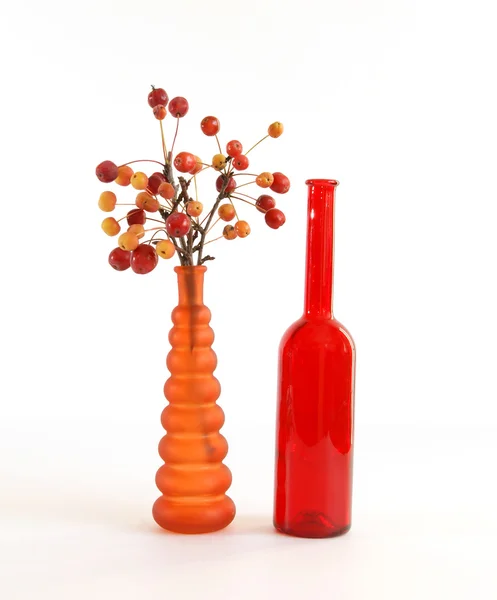 Still life of a branch with small apples in colored glass vase — Stock Photo, Image