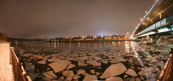 Night panorama of the winter river and a big sports arena