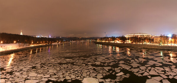 Ночная панорама зимней реки и большой спортивной арены
