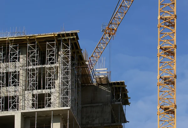 Building crane at the background of a multi-storey building under construct — Stock Photo, Image