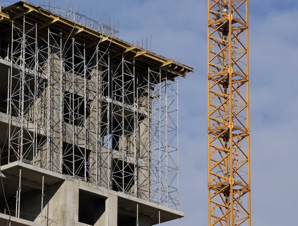 stock image Building crane at the background of a multi-storey building under construct