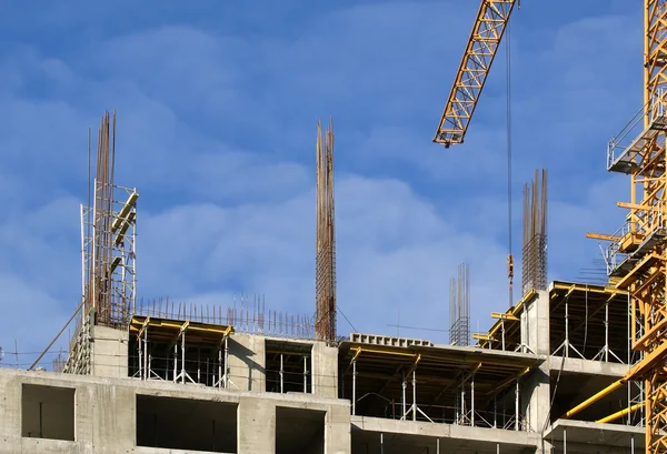 Будівельний кран на тлі багатоповерхового будинку під будівництвом — стокове фото