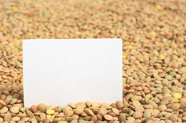 Lentilhas secas cruas com um cartão em branco — Fotografia de Stock