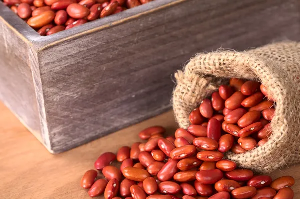 Syrové červené fazole v jutové pytle a dřevěný box — Stock fotografie