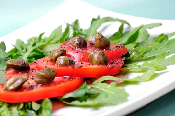 Salad with fresh tomatoes, capers and arugula — Stock Photo, Image