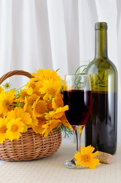 Бутылка розового вина со стаканом и желтыми цветами в башке — стоковое фото