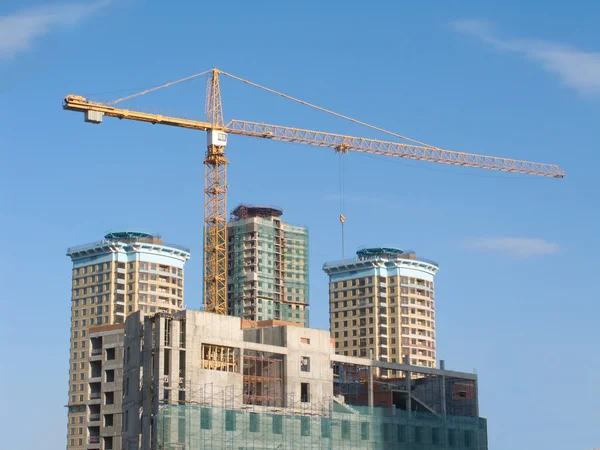 Yellow hoisting crane and some constructing buildings — Stock Photo, Image