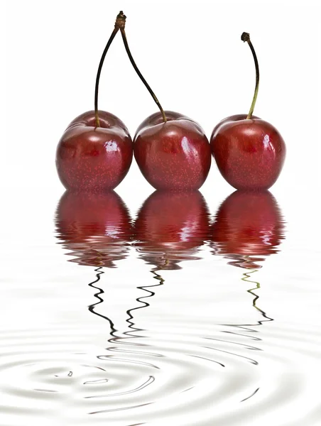 Three cherries reflected on water. — Stock Photo, Image