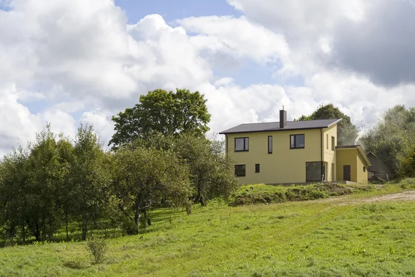 Casa rural amarela em colina verde — Fotografia de Stock