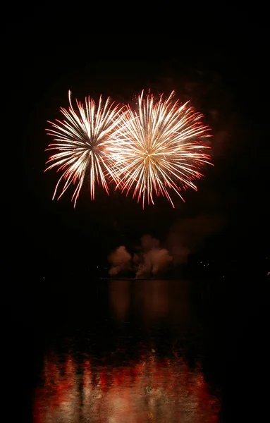 Farbenfrohes Feuerwerk auf dem schwarzen Himmel Hintergrund und Wasser reflektieren — Stockfoto