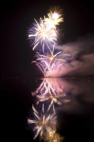Fuochi d'artificio colorati su sfondo cielo nero con riflesso acqua — Foto Stock