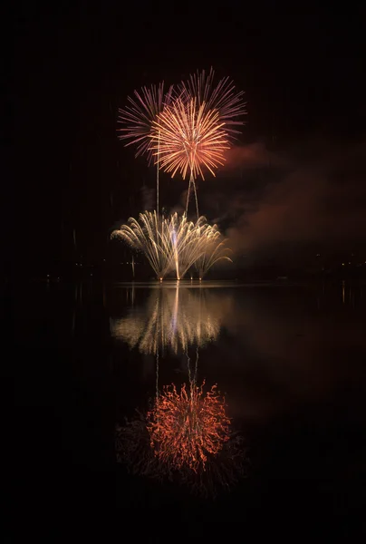 Fogos de artifício coloridos no fundo do céu negro e água refletem — Fotografia de Stock