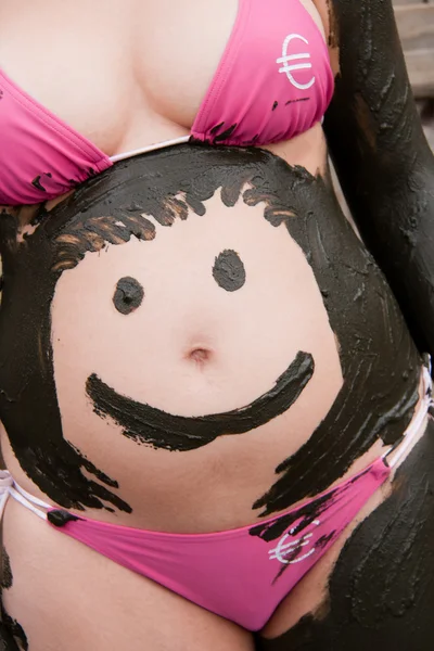 stock image Mud smiley on pregnant woman belly