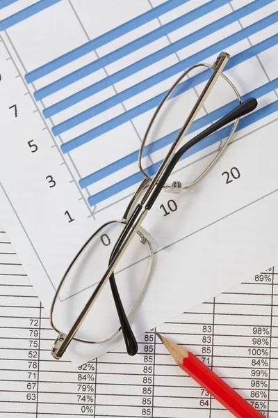 Miniräknare, penna och glasögon på en graf — Stockfoto