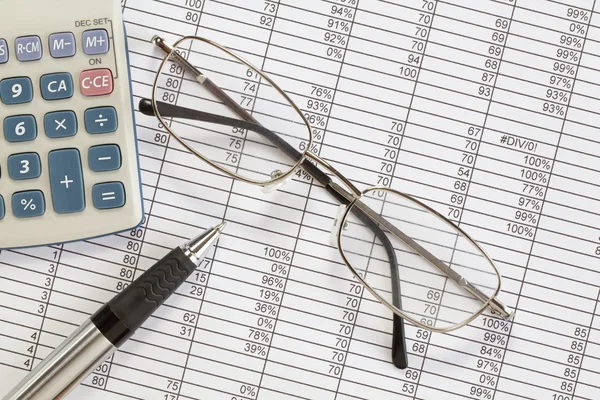 Calculadora, caneta e óculos na planilha — Fotografia de Stock