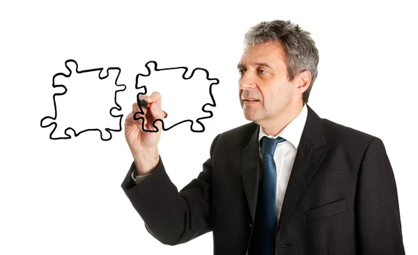 Businessman drawing jigsaw puzzle pieces — Stock Photo, Image