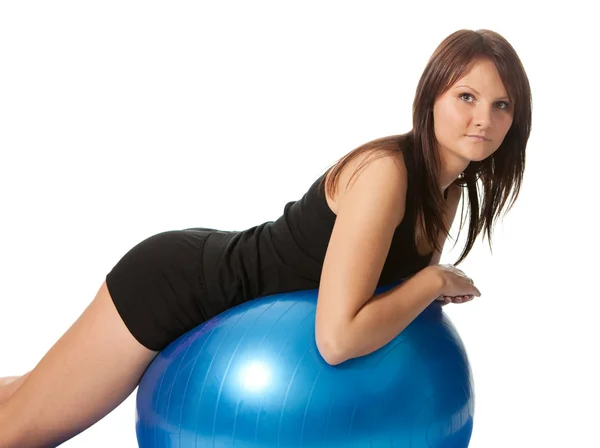 Chica joven que se extiende de nuevo en la pelota de fitness — Foto de Stock