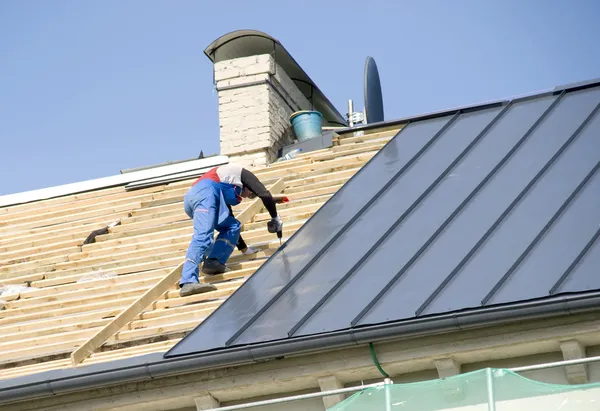 Der Dachdecker hinter der Arbeit an der Reparatur des Daches lizenzfreie Stockbilder