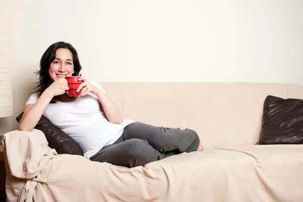 Женщина с напитком на диване — стоковое фото
